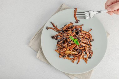 Fırında Shimeji mantarı, baharat ve otlarla dolu bir tabakta. El çatal, vejetaryen yaşam tarzı konsepti, hafif doğal arka plan, düz alan, üst görünüm
