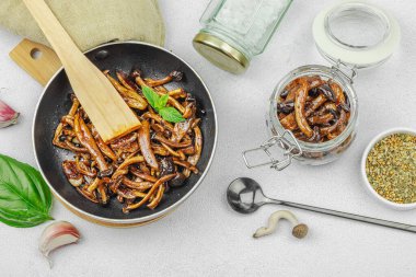 Kahverengi bir tabakta iki sosla servis edilen soslu Shimeji mantarı gurmesi. Sağlıklı bitki temelli yemek, modern mutfak yaşam tarzı, sıcak beton arka plan, üst görünüm.