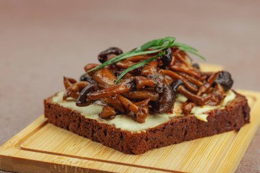 Kahverengi bir tabakta iki sosla servis edilen soslu Shimeji mantarı gurmesi. Sağlıklı bitki temelli yemek, modern mutfak yaşam tarzı, sıcak beton arka plan, üst görünüm.