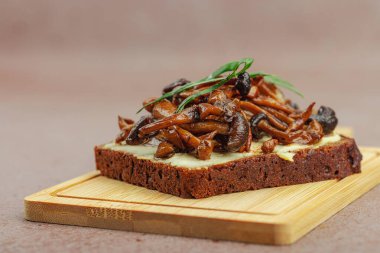 Kahverengi bir tabakta iki sosla servis edilen soslu Shimeji mantarı gurmesi. Sağlıklı bitki temelli yemek, modern mutfak yaşam tarzı, sıcak beton arka plan, üst görünüm.