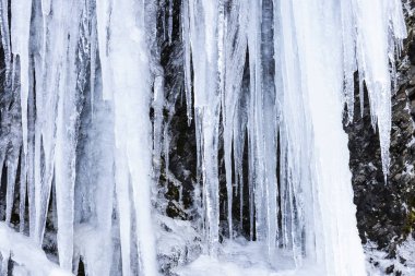 Kayanın üzerinde mavi buz sarkıtları donmuş buz Şelalesi