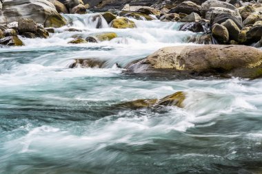Taşların arasından akan bir dere ya da dere manzarası.