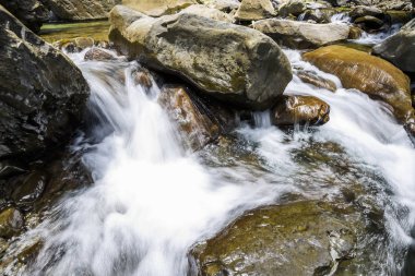 Şelalenin altındaki taşların yakın planında şelale var..