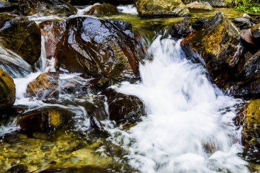 Şelalenin altındaki taşların yakın planında şelale var..