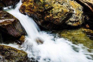 Bir dereye ya da taşların arasından akan akarsuya yakın..