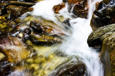 Şelalenin altındaki taşların yakın planında şelale var..