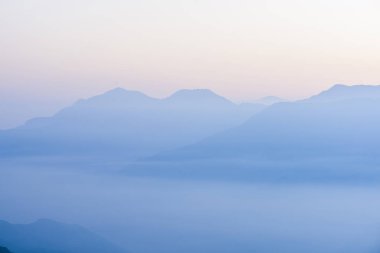 Güneşin doğuşunda muhteşem dağların katmanları ve renkli bulutlar.