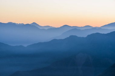 Güneşin doğuşunda muhteşem dağların katmanları ve renkli bulutlar.