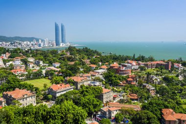 Gulangyu Adası 'nın havadan görünüşü ve Xiamen, Çin kıyıları boyunca uzanan modern binalar..
