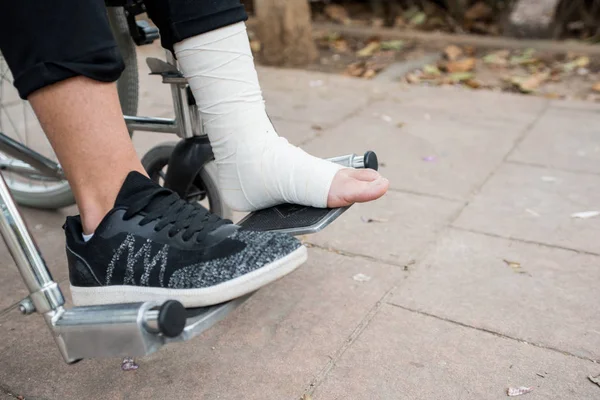 Detail of a foot bandaged in a wheelchair over a brick bottom.