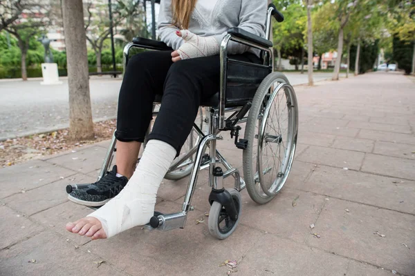 Person injured in a wheelchair. Foot and hand bandages, outdoor photography in a park