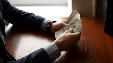 Bir işadamı bir masada sayım yüz dolar faturaları eller. elle izlemek ve ahşap masa dolar. Ekonomi kavramı. adam rüşvet verir