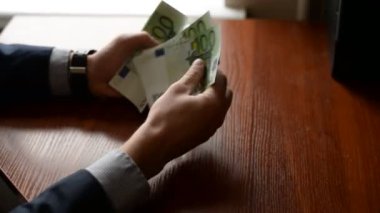 Bir işadamı Close-Up sayım yüz euro faturaları bir masada eller. saati olan adam. çok para. adam rüşvet verir