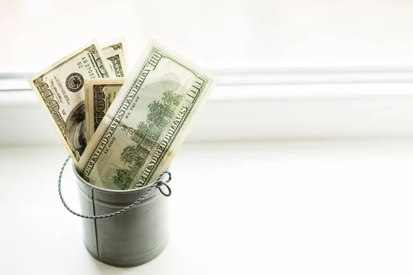 Moneybox, δολάρια σε κουβά στο λευκό παράθυρο. Θέση για κείμενο. Στην κορυφή. Πολλά λεφτά. — Φωτογραφία Αρχείου