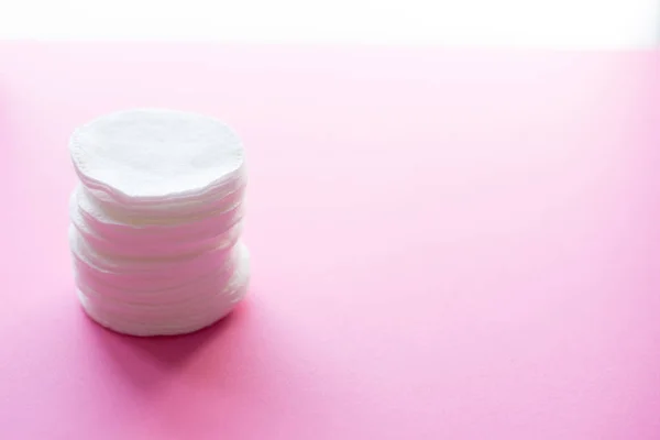 Clean white cotton stack of disk for beauty face hygiene with selective focus on pink neutral background. Cosmetic softness pure sponge for makeup remover. Sterile cleanliness facial sponges — Stock Photo, Image