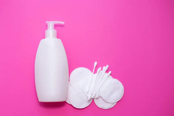 Bottiglia di plastica con lozione, tamponi di cotone e tamponi di cotone su sfondo rosa. pelle, cura del corpo. copia lo spazio. posto per testo — Foto Stock