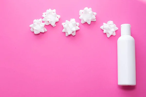 Λευκό πλαστικό σπρέι μπουκαλιού με μικρά λουλούδια σε ροζ φόντο. δέρμα, περιποίηση σώματος. αντίγραφο χώρου. τόπος για κείμενο — Φωτογραφία Αρχείου