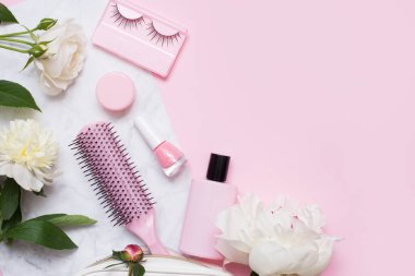 Kozmetik ve çiçeklerle dekoratif düz kompozisyon. Düz yatış, pembe arkaplanda üst görünüm