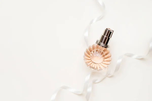 Parfum rose femme dans le flacon entrelacé avec un ruban blanc délicat. arrière-plan avec espace de copie — Photo