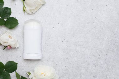 Kadınlar için deodorant ve beyaz güller kopya alanı olan gri masa üzerinde