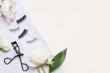 Açık arkaplanda beyaz çiçekli takma kirpikler, üst manzara. Güzellik konsepti. Boşluğu kopyala.