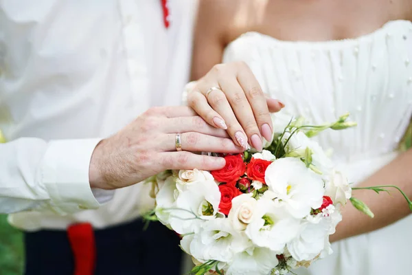 Novias y novios manos con anillos de boda y ramo de bodas — Foto de Stock