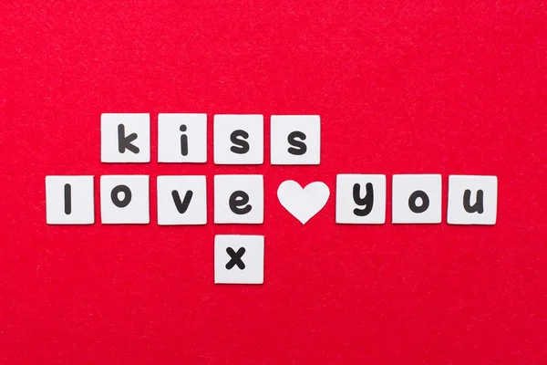Crosswords ,writing the words kiss, love you and sex on red background, letters as in scrabble
