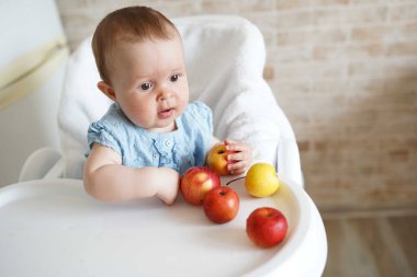 Mutfakta elma yiyen tatlı bir kız bebek. Küçük çocuk evde katı tadı alıyor. Bebek sütten kesilmeye başladı. Çocuklar için sağlıklı beslenme. Boşluğu kopyala