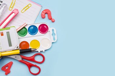 Mavi arkaplanda renkli okul kırtasiyesi ve bir kopya alanı