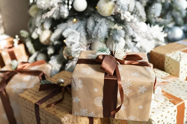 Vánoční dárkové krabice v řemeslném papíru s hnědými stuhami pod jedlí. — Stock fotografie