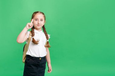 Çılgın, etkileyici, etkileyici küçük kız portresi. Parlak yeşil arka planda işaret parmağı göster.