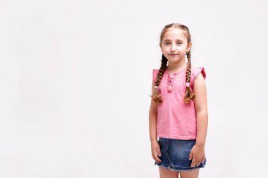 7-8 yaşlarında beyaz arka planda iki örgülü bir kız çocuğu.