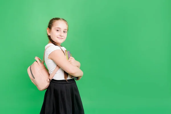 Back to school concept! Half turned close up photo portrait of lovely confident beautiful clever girl with backpack and books on green background