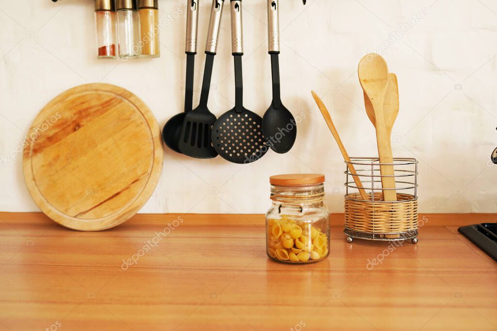 Kitchenware with wooden spoons in vase on wooden table