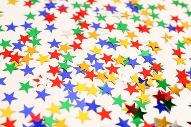 Beyaz arkaplanda çok renkli yıldızlar parıldıyor. Bayram kartı.