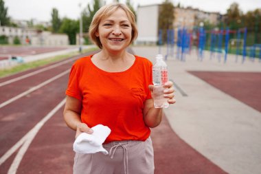 Sportif olgun kadınlar egzersizden sonra su ve havluyla şişeyi dışarıda tutarlar. sağlıklı yaşam tarzı kavramı
