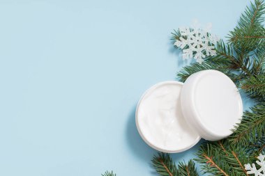 Mavi arka planda kozmetik yüz kremi ya da vücut kremi. Kış bakımı. Boşluğu kopyala