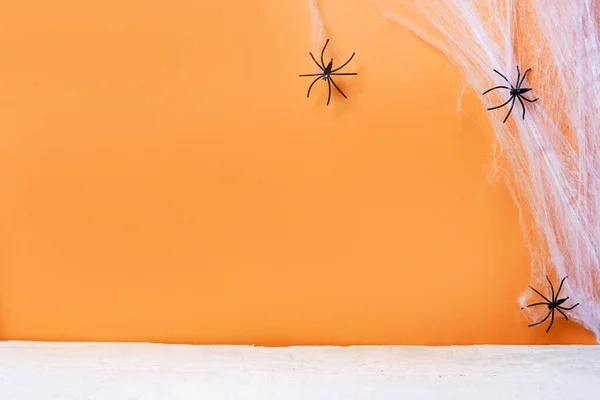 白い木製の床 テキストのための場所とオレンジの背景にハロウィーンのシンボルとしてクモの巣とクモとカード — ストック写真