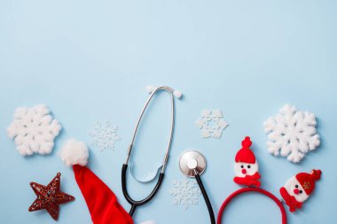 Steteskop ve yeni yıl kırmızı dekor ve kar taneleri ile mavi arka plan, tıbbi kış tatili konsepti.