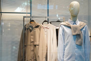 Nötr ve pastel giysiler giymiş bir vitrin mankeni.