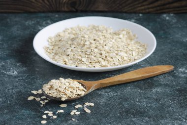 Beyaz plaka üzerinde mavi arka plan ve tahta kaşık yulaf ezmesi