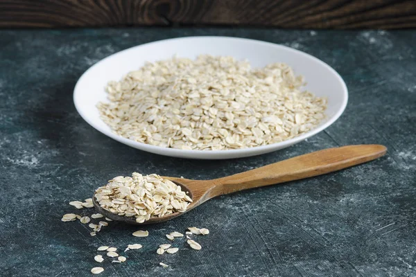 Beyaz plaka üzerinde mavi arka plan ve tahta kaşık yulaf ezmesi