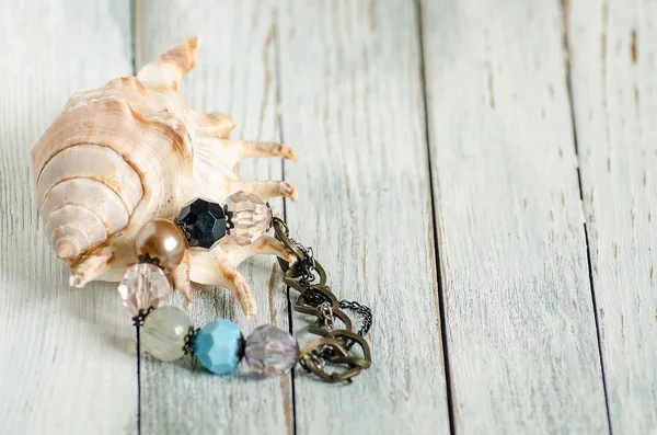 El yapımı bilezik ve deniz kabuğu. Hafif ahşap arka plan. Boşaltmak
