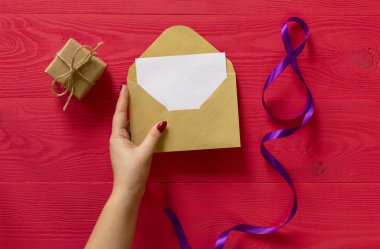 hediye ve 8 Mart için kırmızı ahşap arka plan üzerinde eller mektubu