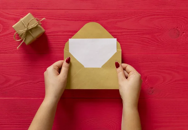 gift and letter of female hands on red wooden background