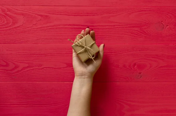 female hands give present on wooden red background