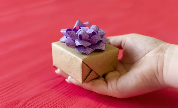 female hands give present on wooden red background