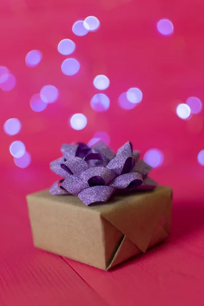 Gift kraft square box with a purple bow on red background