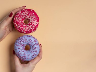 İki donut arka planda tutan kadın el. En az daire yatıyordu, en iyi görünümü kavramı.