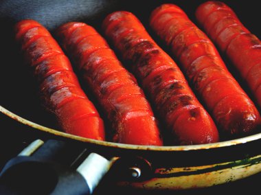 Bir tavayla gri bir yüzey üzerinde mini sosis. Yukarıdan görüntülemek.